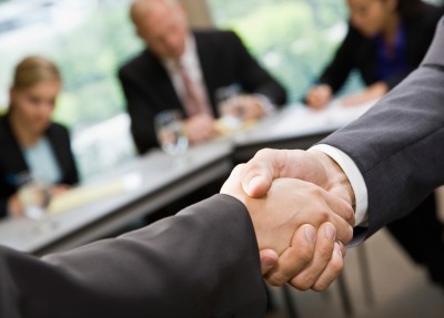 Close up of businessmen shaking hands in conference room