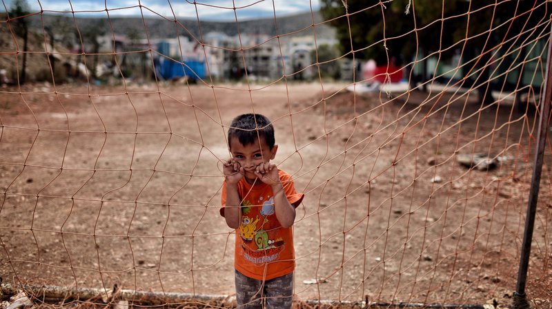A boy looks on behind a net at the refugee camp of Schisto in Athens, Greece, on June 8. Photo: Aris Messinis/AFP/Getty Images