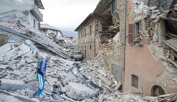 An elderly man in a tracksuit walks on the rubble of a collapsed buildings in Amatrice