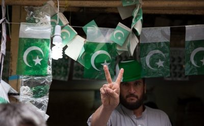 A flag seller poses with the victory sign as flags flutter around him. Photo: Zoral Naik