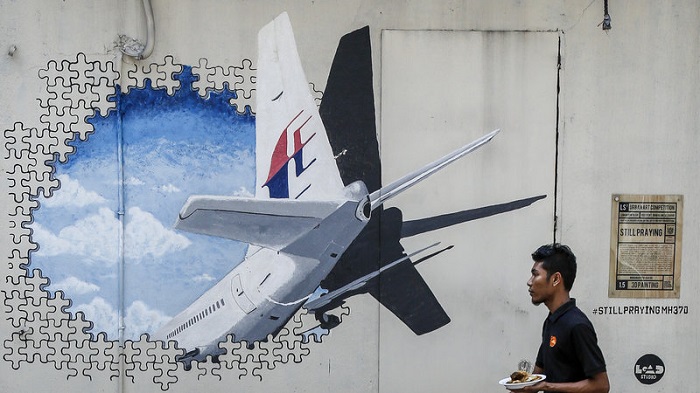 A waiter walks past a mural of Flight MH370 in Shah Alam outside Kuala Lumpur, Malaysia, in February 2016. The flight disappeared nearly three years ago with 239 people on board, and the search for the plane has now been suspended. Photo: Joshua Paul/AP