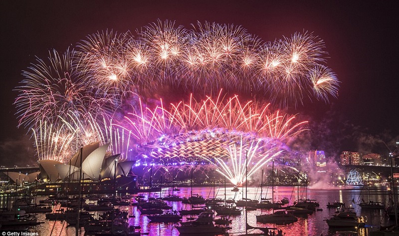 Pink, purple and orange fireworks explode over the Sydney Harbour Bridge and the Sydney Opera House