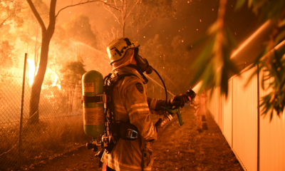 A firefighter hoses down an endangered home in southwest Sydney over the weekend. Photo: AAP