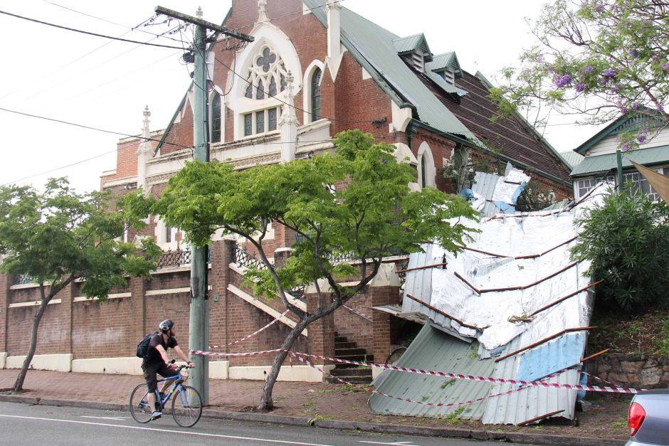 A cyclist rides past the West End Uniting Church that lost its roof in the storm that swept across Brisbane. ABC News: Giulio Saggin