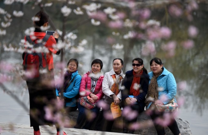 Tourists pose for photos beside cherry trees at the Yuyuantan Park in Beijing. Photo: Xinhua