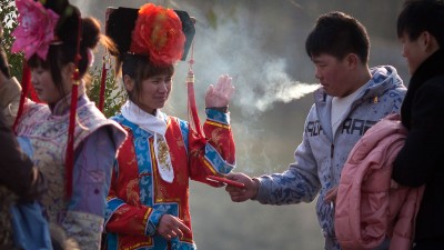 A tourists dressed in Qing dynasty style clothing waves away cigarette smoke in Beihai park in Beijing. Photo: Ed Jones/AFP via Getty Images