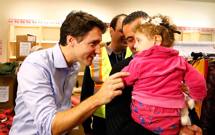 Canada's PM Justin Trudeau speaks with a young girl as he greets a family of Syrian refugees during their arrival at Pearson International airport, in Toronto, on Friday morning. (Nathan Denette/Canadian Press)
