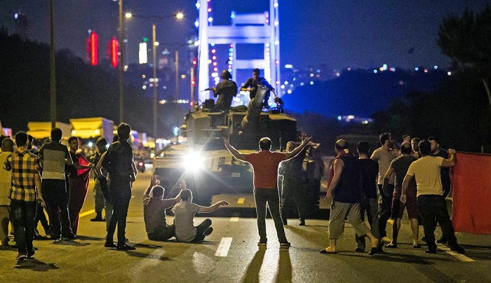 People stand in front of a tank near the Fatih Sultan Mehmet Bridge during clashes with military forces in Istanbul early on July 16. Photo: Gurcan Ozturk/AFP/Getty Images