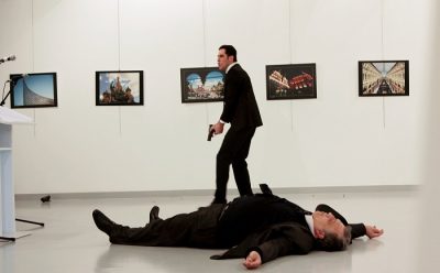 A man, reported by The Associated Press to be the gunman, after the shooting of the Russian ambassador, on the floor, on Monday at a gallery in Ankara, the capital of Turkey. Credit Hasim Kilic/Hurriyet, via Reuters